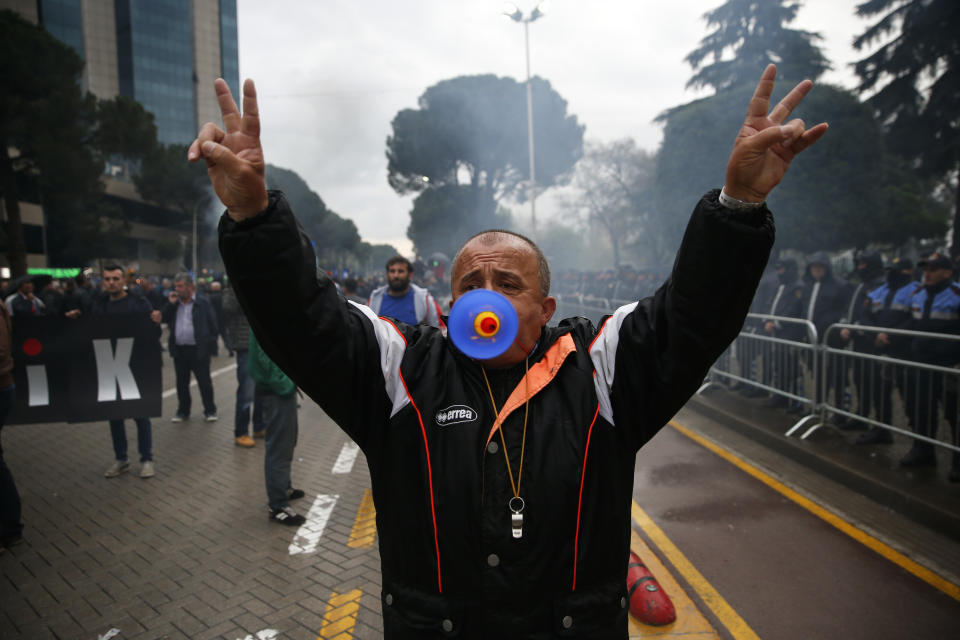 A protester blows a horn as he gestures, during an anti-government protest in the capital Tirana, Saturday, April 13, 2019. Albanian opposition parties have returned to the streets for the first time since mid-February calling for the government's resignation and an early election, as the center-right opposition accuses the leftist Socialist Party government of Prime Minister Edi Rama of corruption and links to organized crime, which the government denies. (AP Photo/Visar Kryeziu)