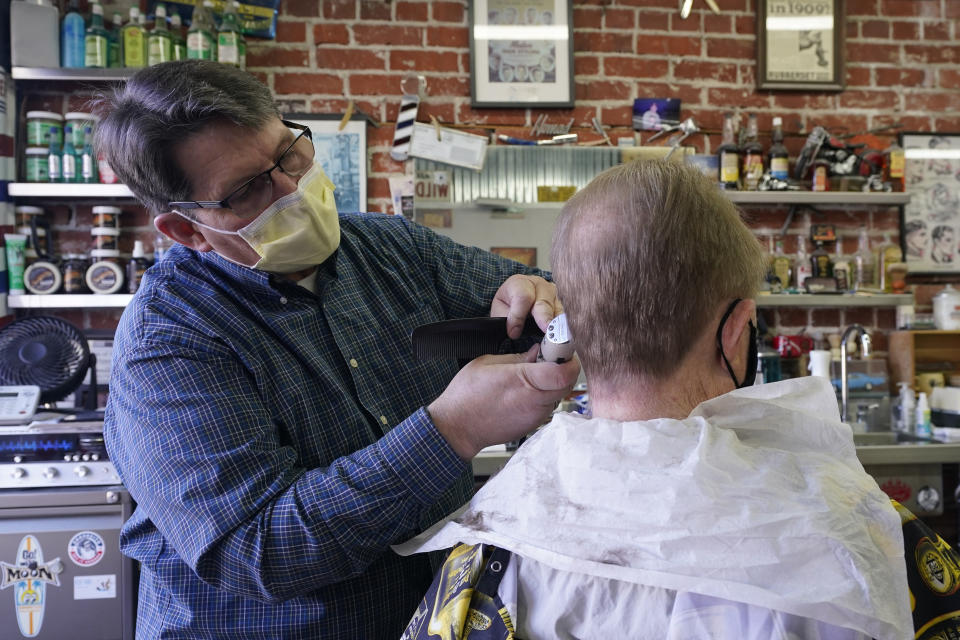 FILE — In this Thursday Jan. 21, 2021 file photo Mike Douglass, left, gives Kent Kjestrom a haircut at East J Barbers in Sacramento, Calif. California Health and Human Services Secretary Dr. Mark Ghaly explained the math behind the state's calculation of when it is safe to lift it's stay-at-home order and overnight curfew, during a news briefing Tuesday, Jan. 26, 2021. (AP Photo/Rich Pedroncelli, File)