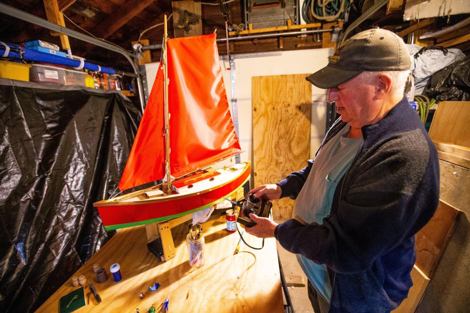 George Jewell tests the remote control on his radio-controlled sailboat in the workshop at his South Bend home.