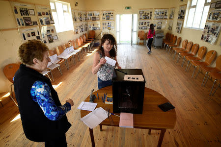 Presiding Officer Carmel McBride looks on as a voter casts their vote in the polling box for the referendum on liberalising abortion law a day early for the few people that live off the coast of Donegal on the island of Inishbofin, Ireland May 24, 2018. REUTERS/Clodagh Kilcoyne