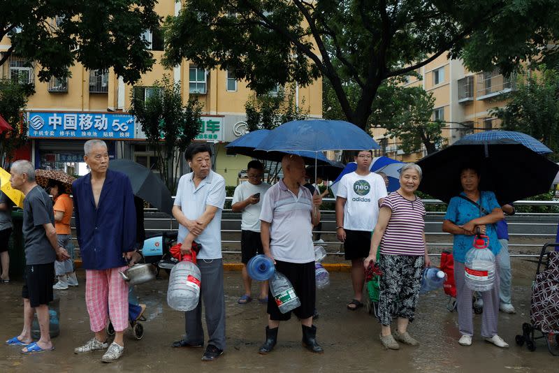 Gente hace cola para conseguir agua potable en un barrio donde el tifón Doksuri causó inundaciones, en Pekín, China