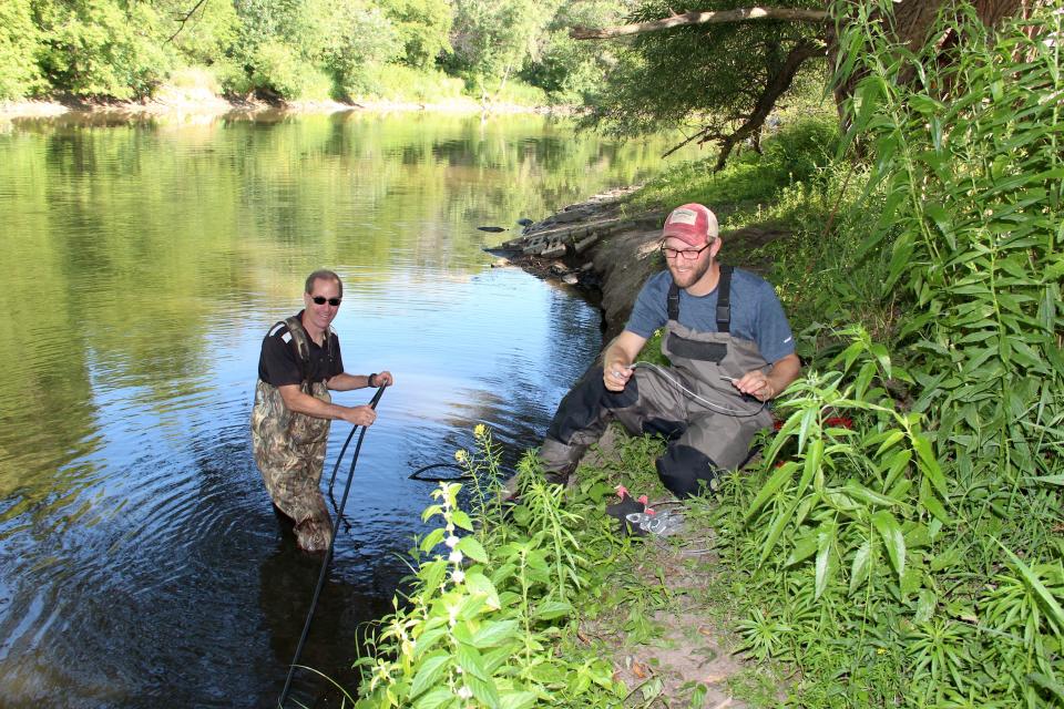 Fisheries manager Brad Eggold, left, and fisheries biologist Aaron Schiller, both of the Wisconsin Department of Natural Resources, work to secure cables of a passive integrated transponder (or PIT) tag array on the Milwaukee River last summer.