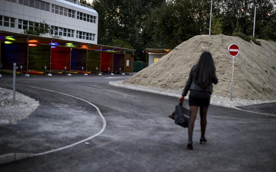 A prostitute walks past so-called "sex boxes" at the opening day of Switzerland's first sex drive-in on August 26, 2013 in Zurich, which is aiming to get prostitution off the city streets. The drive-in, which as darkness began to fall was bathed in colourful lights, has a track where the sex workers can show off their assets and negotiate a price, and nine so-called "sex boxes" where they and their clients can park and conclude the transaction. AFP PHOTO / FABRICE COFFRINI (Photo credit should read FABRICE COFFRINI/AFP/Getty Images) - FABRICE COFFRINI /AFP