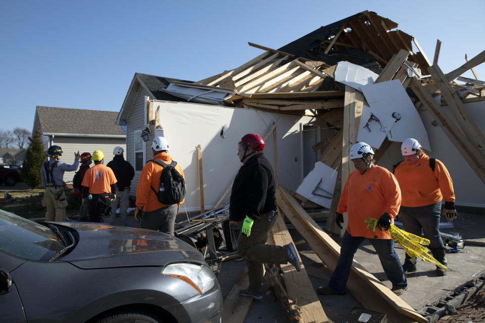 Search and rescue workers go house to house Tuesday, Dec. 14, 2021, in Bowling Green, Ky. When a tornado touched down in Bowling Green in the middle of the night, its violence was centered on a friendly subdivision. Fourteen people died in a few blocks, 11 of them on a single street. (AP Photo/James Kenney)