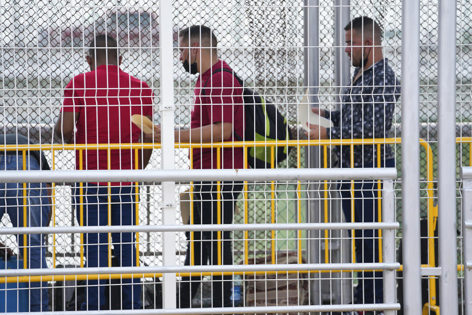 Migrants hold documents as they wait for their appointments to be processed by U.S. immigration officials on the McAllen-Hidalgo International Bridge, Friday, May 12, 2023, in Hidalgo, Texas. (AP Photo/Julio Cortez)