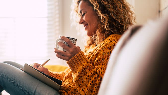 Happy cute lady at home write notes on a diary while drink a cup of tea and rest and relax taking a break.