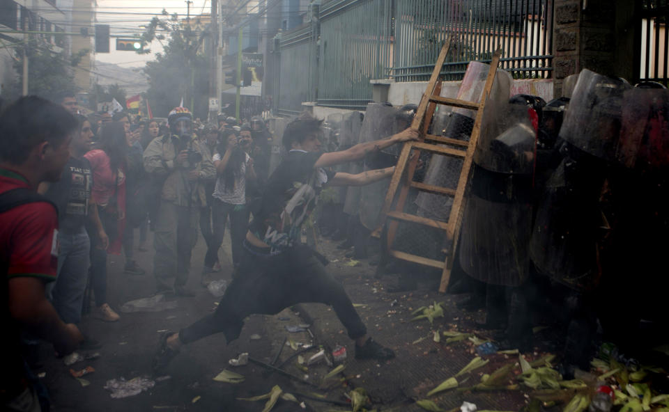 Un opositor al gobierno del presidente Evo Morales arroja una escalera a la policía que resguarda el Tribunal Electoral durante una huelga nacional en La Paz, Bolivia, el jueves 6 de diciembre de 2018. (AP Foto/Juan Karita)