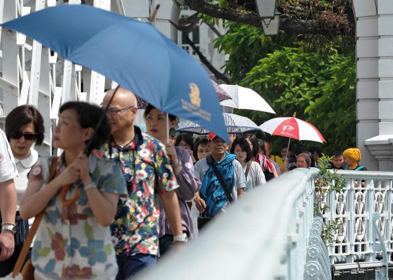 Tourists walk across Anderson bridge in the financial district of Singapore, on June 24, 2014