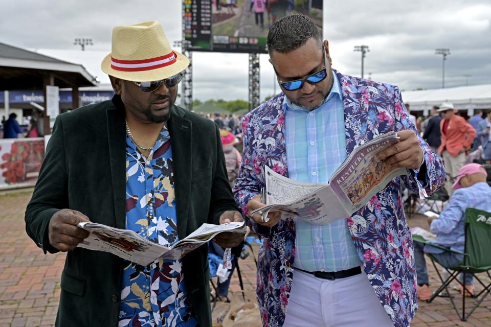 May 7, 2022; Louisville, KY; Vishal Singh and Andrew Gansalves check the betting sheets before the 148th running of the Kentucky Derby at Churchill Downs. Photo: Jamie Rhodes-USA TODAY Sports