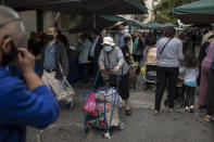 People wearing face masks to curb the spread of coronavirus walk at an open air fruit and vegetable market in Petralona district of Athens, on Wednesday, Nov. 4, 2020. Greece, on Tuesday reported a new record of over 2,000 daily COVID-19 infections, and a further 13 deaths – which bring the overall death toll to over 650. (AP Photo/Petros Giannakouris)