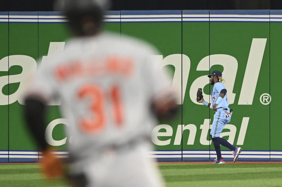 Toronto Blue Jays right fielder Raimel Tapia, right, catches a fly ball off the bat of Baltimore Orioles' Cedric Mullins, left foreground, in first-inning baseball game action in Toronto, Sunday, Sept. 18, 2022. (Jon Blacker/The Canadian Press via AP)