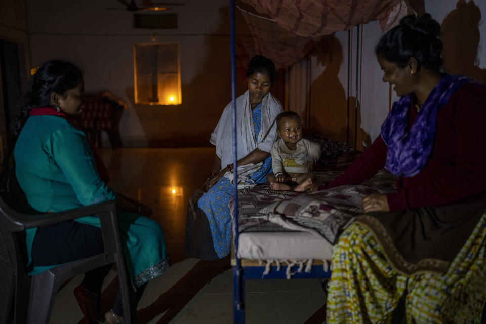 Basanti Warda, right, who works at an early referral center, plays with one-year-old Dilesh, as his mother Phagni Poyam, 23, a nine months pregnant woman, looks on inside an early referral center in Orchha in central India's Chhattisgarh state, Nov. 15, 2022. These ambulances, first deployed in 2014, reach inaccessible villages to bring pregnant women to an early referral center, a building close to the hospital where expectant mothers can stay under observation, routinely visit doctors if needed until they give birth. Since then the number of babies born in hospitals has doubled to a yearly average of about 162 births each year, from just 76 in 2014. The state has one of the highest rates of pregnancy-related deaths for mothers in India, about 1.5 times the national average, with 137 pregnancy related deaths for mothers per 100,000 births. (AP Photo/Altaf Qadri)