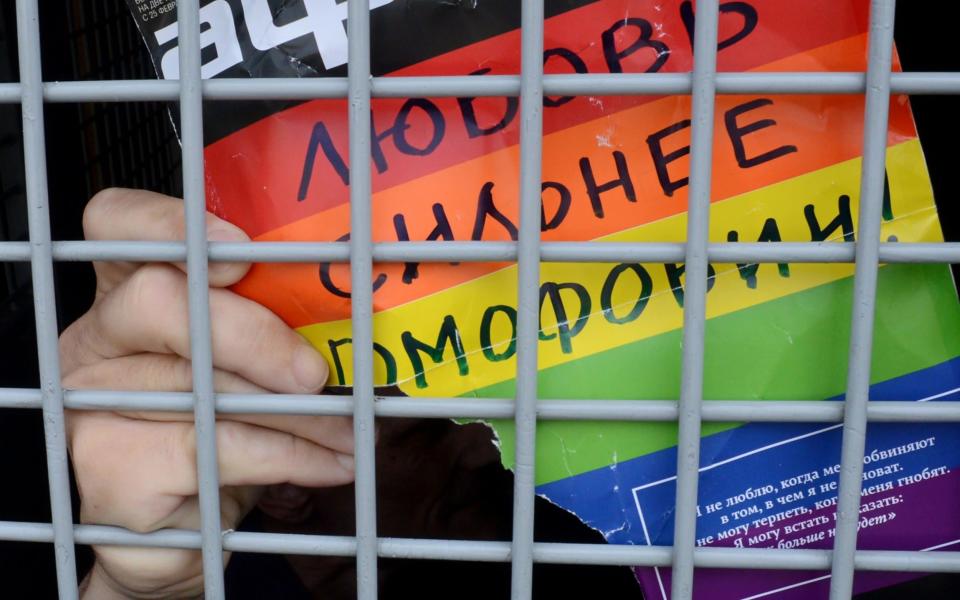 A Russian gay rights activist holds a poster reading 'love is stronger than homophobia!' from inside a police van after his detention during an unauthorized gay rights activists rally in central Moscow in 2013. Earlier that year President Vladimir Putin signed a law banning the dissemination of