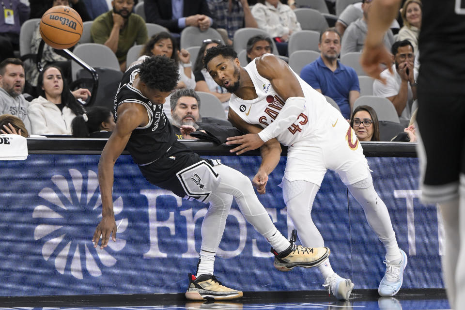 Cleveland Cavaliers' Donovan Mitchell, right, and San Antonio Spurs' Josh Richardson run into the scorer's table during the second half of an NBA basketball game, Monday, Dec. 12, 2022, in San Antonio. San Antonio won 112-111. (AP Photo/Darren Abate)