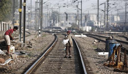 A ragpicker boy walks on the tracks as he searches for plastic bottles for reselling, at a railway station in New Delhi February 18, 2014. REUTERS/Adnan Abidi