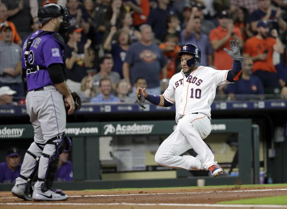 Houston Astros' Yuli Gurriel (10) scores as Colorado Rockies catcher Chris Iannetta looks toward the outfield during the first inning of a baseball game Wednesday, Aug. 15, 2018, in Houston. (AP Photo/David J. Phillip)