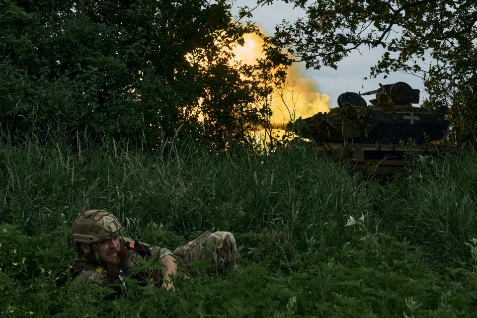June 17, 2023 : A Ukrainian soldier lies on the ground as a tank fires toward Russian positions at the frontline near Bakhmut, Donetsk region, Ukraine.