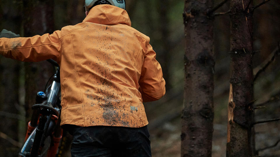 Rear view of mountain biker in mud spattered jacket