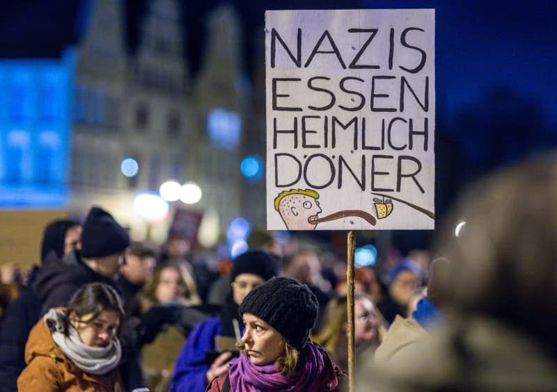 A person holds a placard during a demonstration against right-wing extremism under the slogan "Never again is now - all together against fascism" on the Neuer Markt in front of the town hall. Jens Büttner/dpa