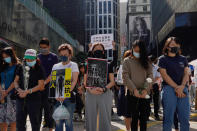 Protesters observe a moment of silence with banners some of which reads "Disband the police force" and "You are not police officers, you are murderers" during a memorial flash mob to remember Chow Tsz-Lok in Hong Kong on Friday, Nov. 8, 2019. Chow, a Hong Kong university student who fell off a parking garage after police fired tear gas during clashes with anti-government protesters died Friday, in a rare fatality after five months of unrest that intensified anger in the semi-autonomous Chinese territory. (AP Photo/Vincent Yu)