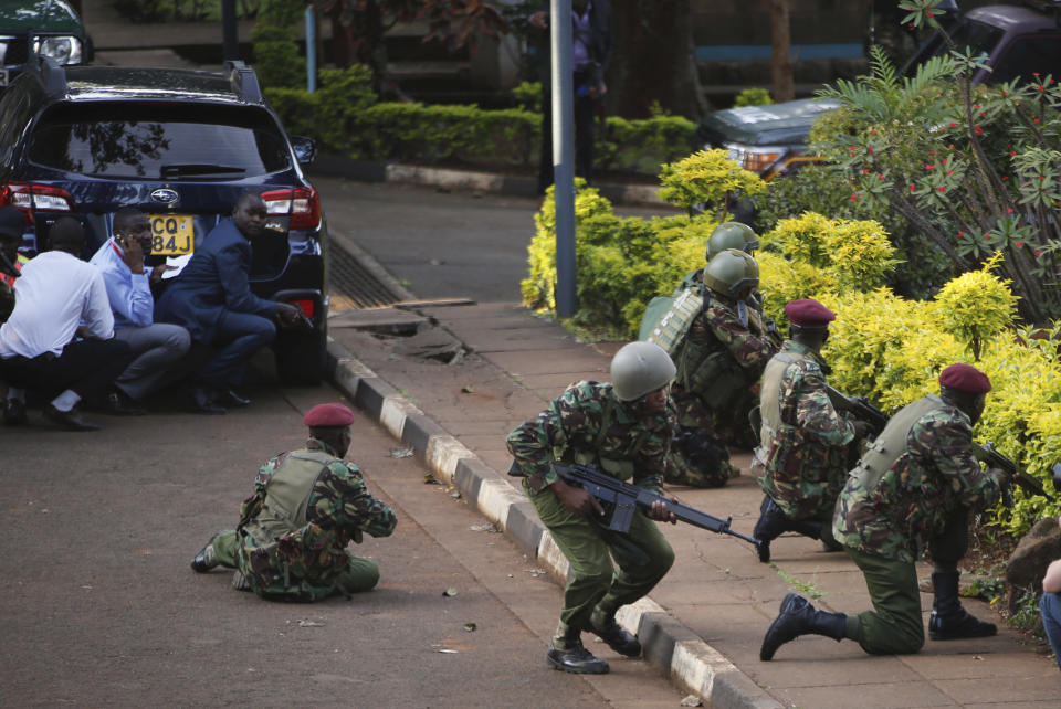 Kenyan armed forces and civilian people take cover after an attack on a hotel, in Nairobi, Kenya, Tuesday, Jan. 15, 2019. Extremists launched a deadly attack on a luxury hotel in Kenya's capital Tuesday, sending people fleeing in panic as explosions and heavy gunfire reverberated through the complex. A police officer said he saw bodies, "but there was no time to count the dead." (AP Photo/Brian Inganga)