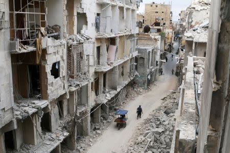 Residents walk near damaged buildings in the Old City of Aleppo, Syria May 5, 2016. REUTERS/Abdalrhman Ismail