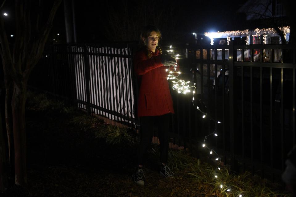 Youth from Redeemer Church of Knoxville assist in decorating a railing at Light Up Lonsdale, put on by Thrive in Lonsdale, Wednesday, Nov. 29, 2023.