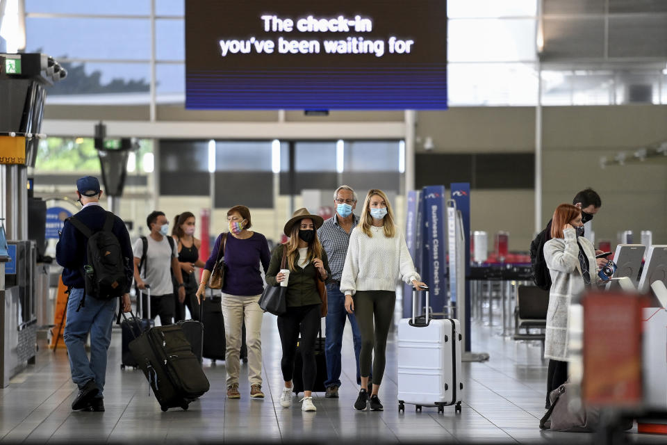 Passengers wear face masks as they arrive at the departures terminal at Sydney Domestic Airport in Sydney, Australia Friday, Nov. 5, 2021. Flights between New South Wales and Victoria have resumed without any COVID-19 restrictions, as the border between the two states reopens. (Bianca De Marchi/AAP Image via AP)