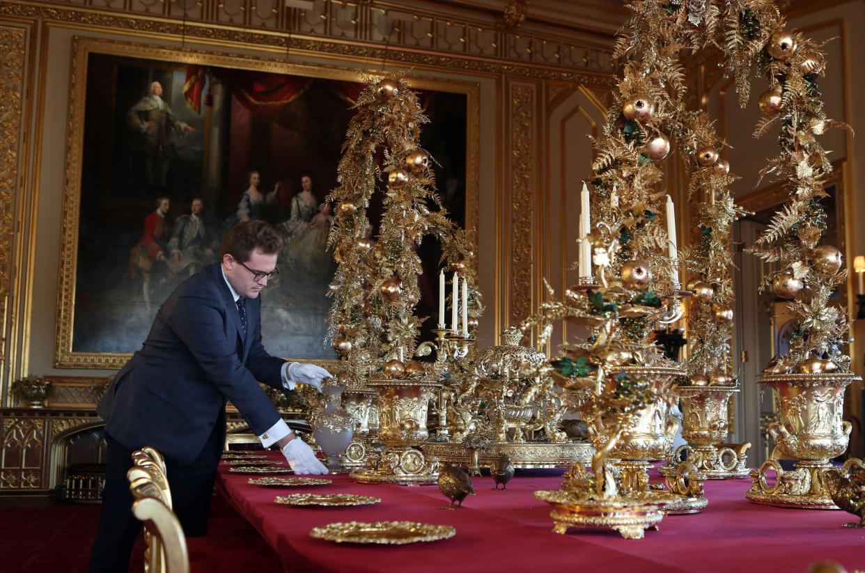 A member of Royal Collection Trust staff applys the finishing touches to the table in the State Dining Room, at Windsor Castle, Berkshire. Set with silver-gilt pieces from the spectacular Grand Service, commissioned by George IV and still used today by The Queen and her guests at State Banquet. (Photo by Steve Parsons/PA Images via Getty Images)