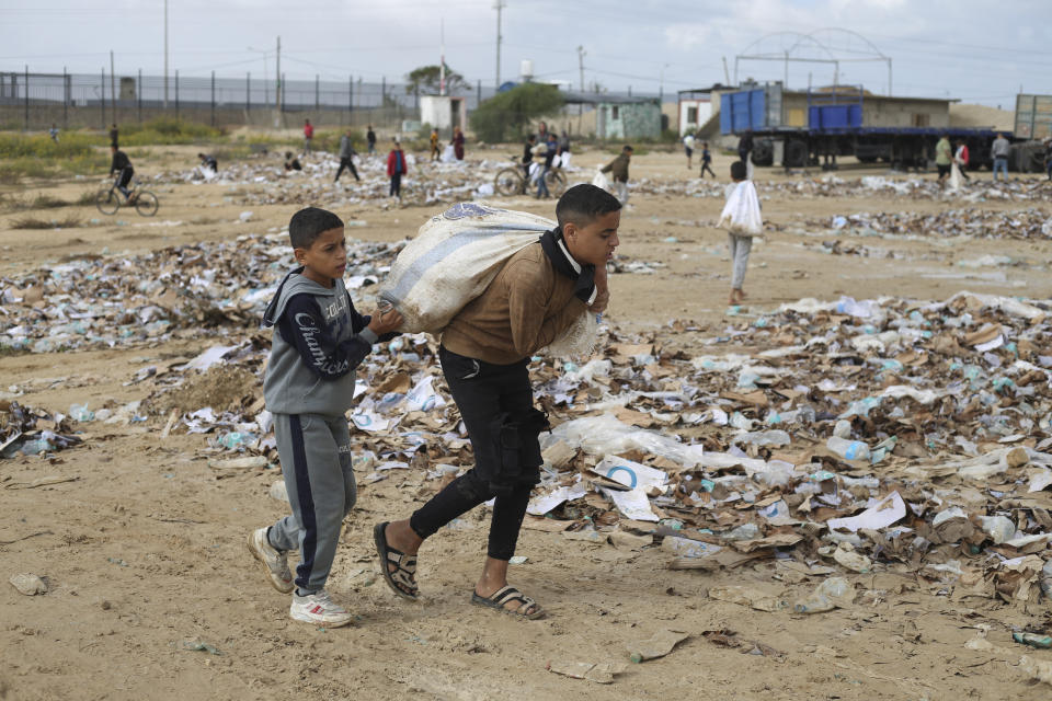 A Palestinian boy carries water looted from the humanitarian aid trucks during the ongoing Israeli bombardment of the Gaza Strip at the border with Egypt in Rafah on Monday, Nov. 20, 2023. (AP Photo/Hatem Ali)