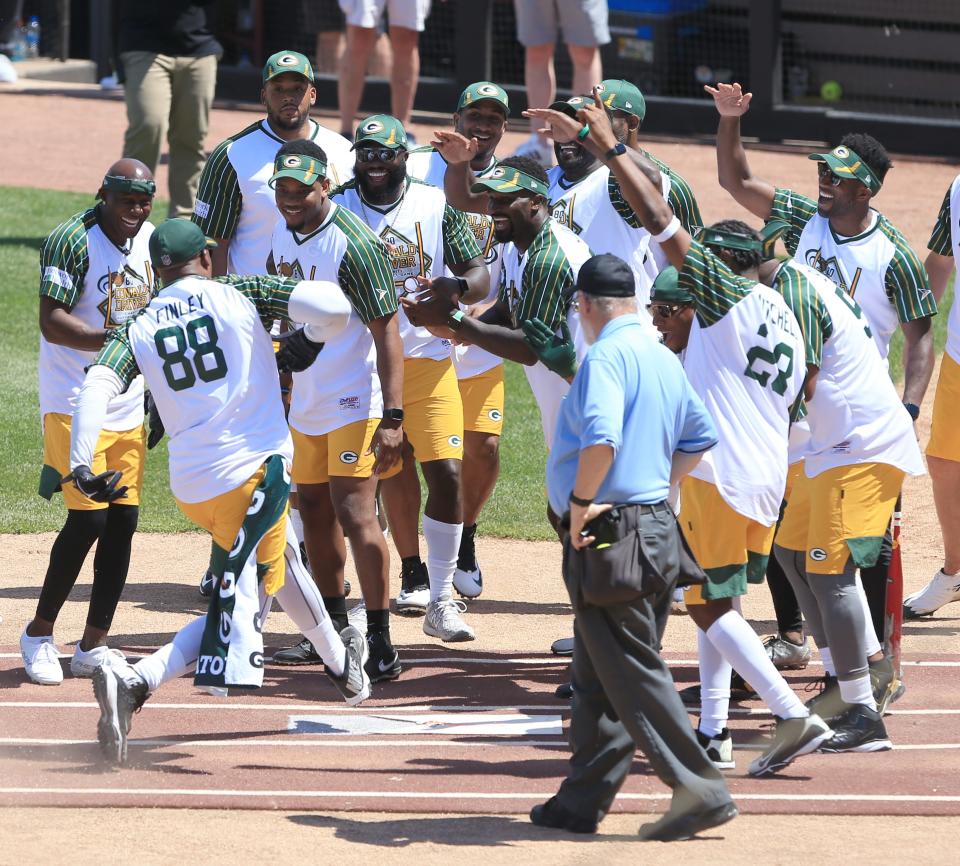 Former Green Bay Packers tight end Jermichael Finley is greeted by his teammates after scoring during the Donald Driver Charity Softball Game on Sunday at Neuroscience Group Field at Fox Cities Stadium in Grand Chute.