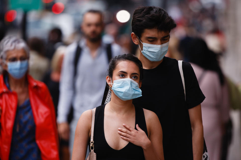 A man and woman wearing face masks walk along Regent Street in London, England, on September 22, 2020. British Prime Minister Boris Johnson this afternoon announced a raft of new coronavirus restrictions to apply across England, possibly to last the next six months, including requiring pubs and restaurants to close at 10pm and for retail staff to all wear face masks. A return to home working where possible is also being encouraged. The new measures come amid fears of a 'second wave' of covid-19 deaths prompted by rising numbers of people testing positive in recent weeks. (Photo by David Cliff/NurPhoto via Getty Images)