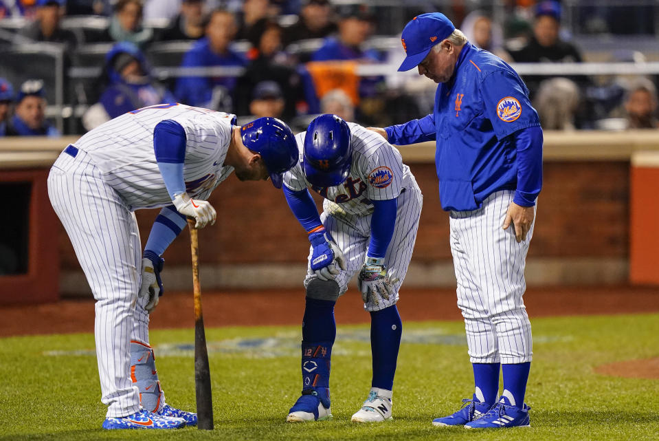 New York Mets manager Buck Showalter, right, and Pete Alonso check on Francisco Lindor (12) as he hunches over after fouling a ball off his knee during the fourth inning of Game 3 of a National League wild-card baseball playoff series against the San Diego Padres, Sunday, Oct. 9, 2022, in New York. (AP Photo/Frank Franklin II)