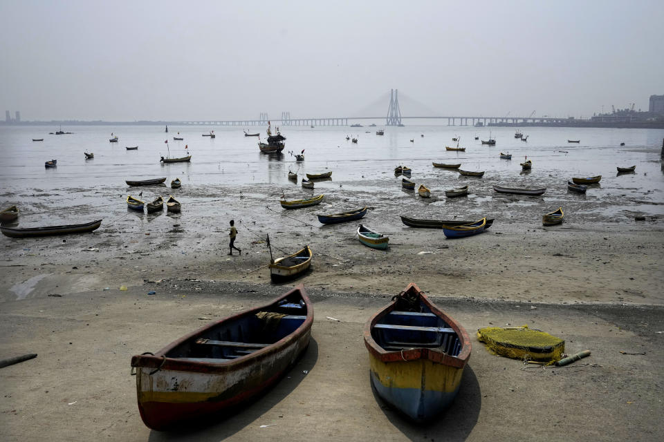 A boy walks past fishing boats at Mahim in Mumbai, India, Friday, March 17, 2023. India, with over 1.4 billion people, is set to eclipse China to become the largest - and youngest - population in the world in April. Its demographic rise has coincided with a swelling economy that is the fastest-growing in the world. (AP Photo/Rajanish Kakade)