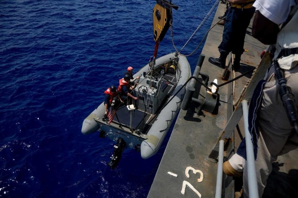 Sailors lower a rigid-hull inflatable boat