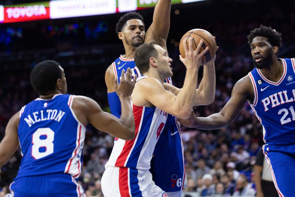 Pistons forward Bojan Bogdanovic drives for a shot against 76ers forward Tobias Harris, center, and center Joel Embiid, right, during the first quarter on Wednesday, Dec. 21, 2022, in Philadelphia.