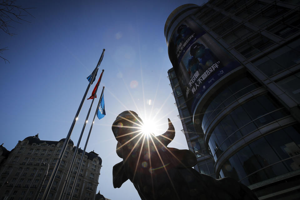 A statue of a bull, an investment icon, stands outside an office building with a screen showing propaganda about fighting against Coronavirus in Beijing, Tuesday, March 10, 2020. Asian stock markets took a breather from recent steep declines on Tuesday, with several regional benchmarks gaining more than 1% after New York futures reversed on news that President Donald Trump plans to ask Congress for a tax cut and other quick measures to ease the pain of the virus outbreak. (AP Photo/Andy Wong)