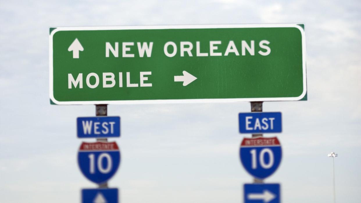 interstate 10 sign for mobile and new orleans, cities that both claim to have held the first mardi gras in the united states