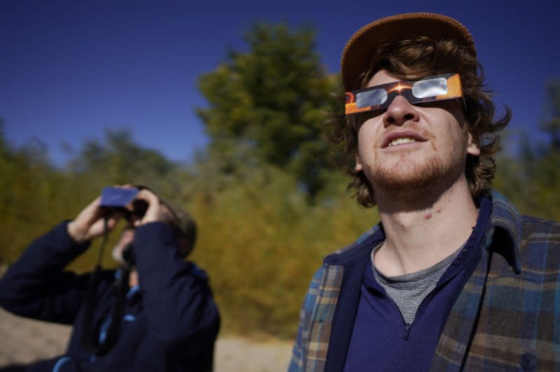 Tim and Simon Viavant (R) watch as the Moon covers the Sun during an annular 'Ring of Fire' solar eclipse near Bluff, Utah on Saturday. Photo by Bob Strong/UPI