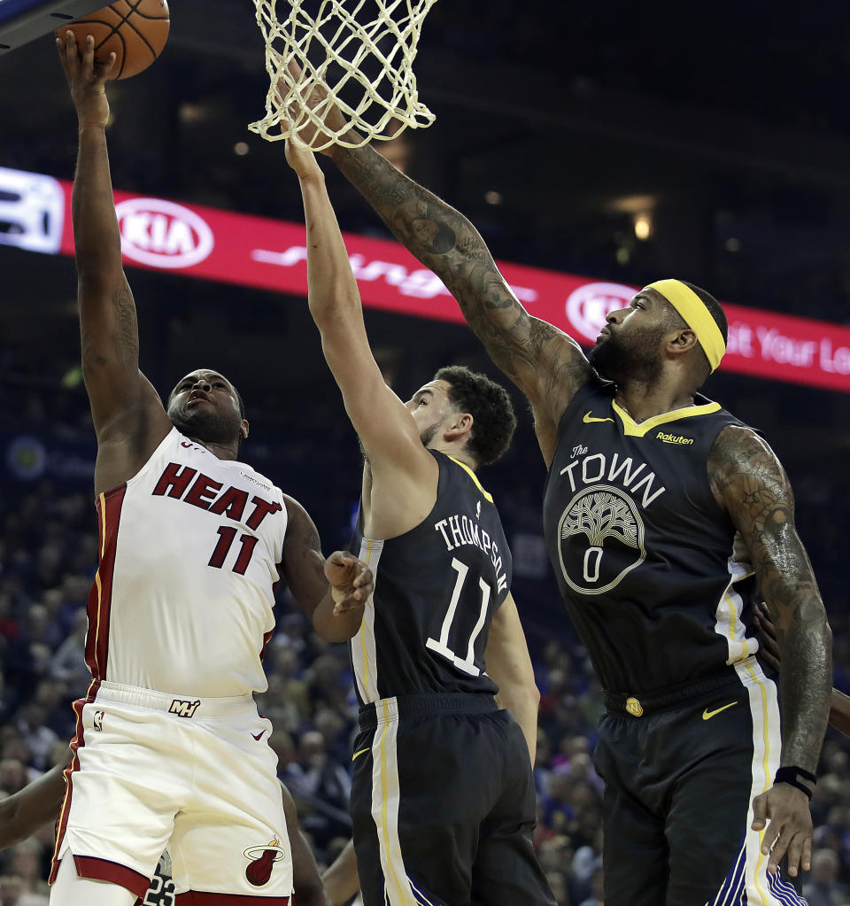 Miami Heat guard Dion Waiters, left, shoots against Golden State Warriors' Klay Thompson, center, and DeMarcus Cousins (0) during the first half of an NBA basketball game, Sunday, Feb. 10, 2019, in Oakland, Calif. (AP Photo/Ben Margot)