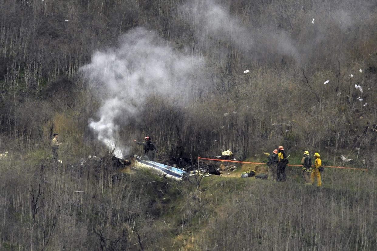 FILE - In this Jan. 26, 2020, file photo, firefighters work the scene of a helicopter crash in Calabasas, Calif. Federal safety officials are expected to vote Tuesday, Feb. 9, on what likely caused the helicopter carrying Kobe Bryant, his 13-year-old daughter and seven others to crash into a Southern California hillside last year, killing all aboard. 
