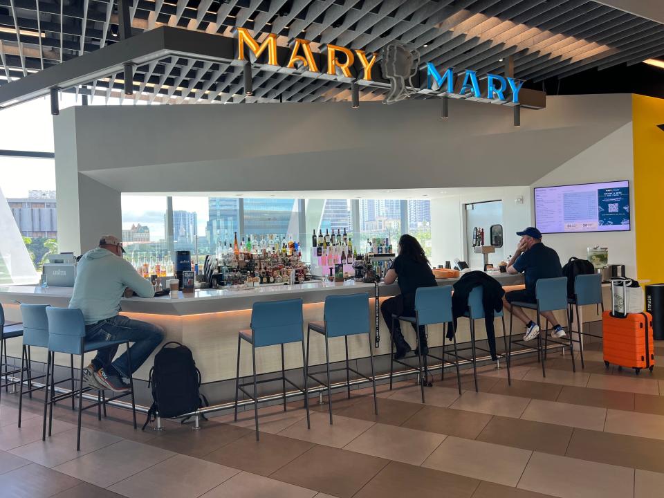 The Mary Mary bar at the Fort Lauderdale Brightline station is shown. A few patrons sit on blue barstools.