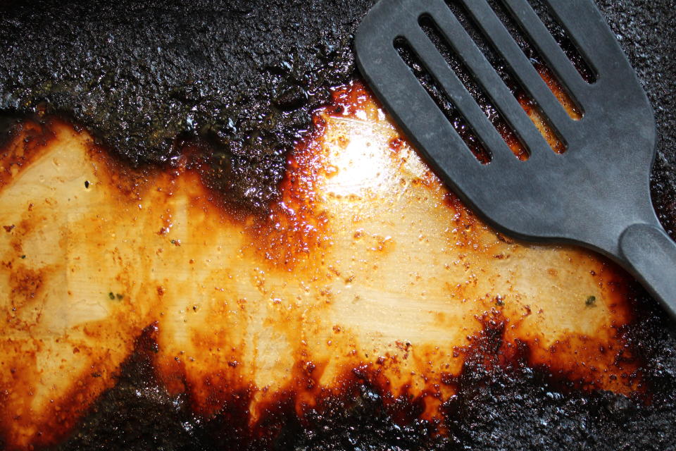 Top-down view of burnt glass baking dish with spatula.