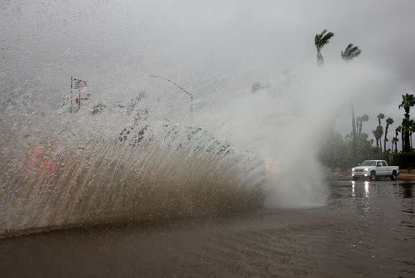 CATHEDRAL CITY, CALIFORNIA - AUGUST 20: A vehicle drives through a flooded street as Tropical Storm Hilary moves through the area on August 20, 2023 in Cathedral City, California. Southern California is under a first-ever tropical storm warning as Hilary impacts parts of California, Arizona and Nevada. All California state beaches have been closed in San Diego and Orange counties in preparation for the impacts from the storm which was downgraded from hurricane status. (Photo by Mario Tama/Getty Images)