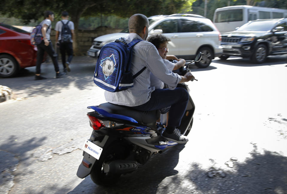 A man with his son on a scooter after the end of the school day in Beirut, Lebanon, Wednesday, Sept. 29, 2021. This fall, Lebanon's schools have been gripped by the same chaos that has overwhelmed everything else in the country in its historic economic meltdown. The start of the academic year has been postponed repeatedly because thousands of teachers are on strike, demanding adjustments in their salary to cope with hyperinflation. (AP Photo/Bilal Hussein)