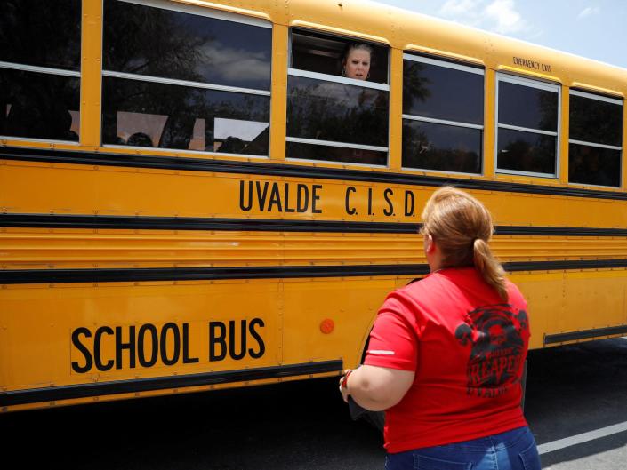 A school employee talks through the window of a school bus at Robb Elementary School