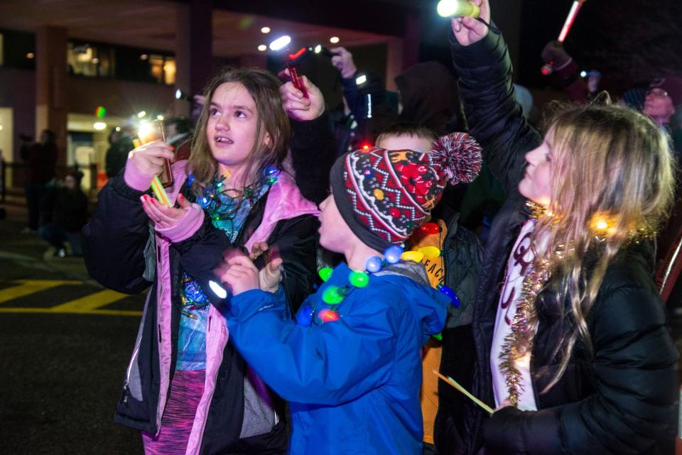 This trio partakes in the festivities with their eyes and flashlights lifted upwards to the pediatric unit at Corewell Health William Beaumont University Hospital, formerly Beaumont, Royal Oak.