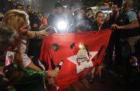 <p>Demonstranten im brasilianischen Sao Paolo zünden eine Flagge der Arbeiterpartei an, die eine Karikatur des brasilianischen Ex-Präsidenten Lula da Silva in Sträflingskleidung zeigt. Sie feiern damit die Entscheidung des Richters Sergio Moro, der da Silva der Korruption und Geldwäsche schuldig sprach und ihn zu fast zehn Jahren Haft verurteilte. (Bild: AP Photo/Andre Penner) </p>