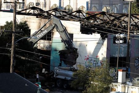 A crane removes debris from the site of a fatal warehouse fire in Oakland, California, U.S. December 6, 2016. REUTERS/Stephen Lam