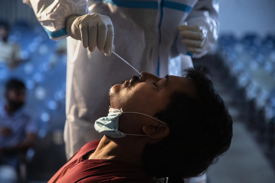 A health worker takes the nasal swab sample of an election official to test for COVID-19 on the eve of state elections results in Gauhati, India, Saturday, May 1, 2021. India on Saturday set yet another daily global record with 401,993 new cases, taking its tally to more than 19.1 million. Another 3,523 people died in the past 24 hours, raising the overall fatalities to 211,853, according to the Health Ministry. Experts believe both figures are an undercount. (AP Photo/Anupam Nath)